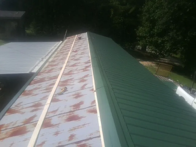 Old rusted panels beside newly installed green metal roofing — Wind Damage Roof Repair by Roofing Brothers in Barboursville