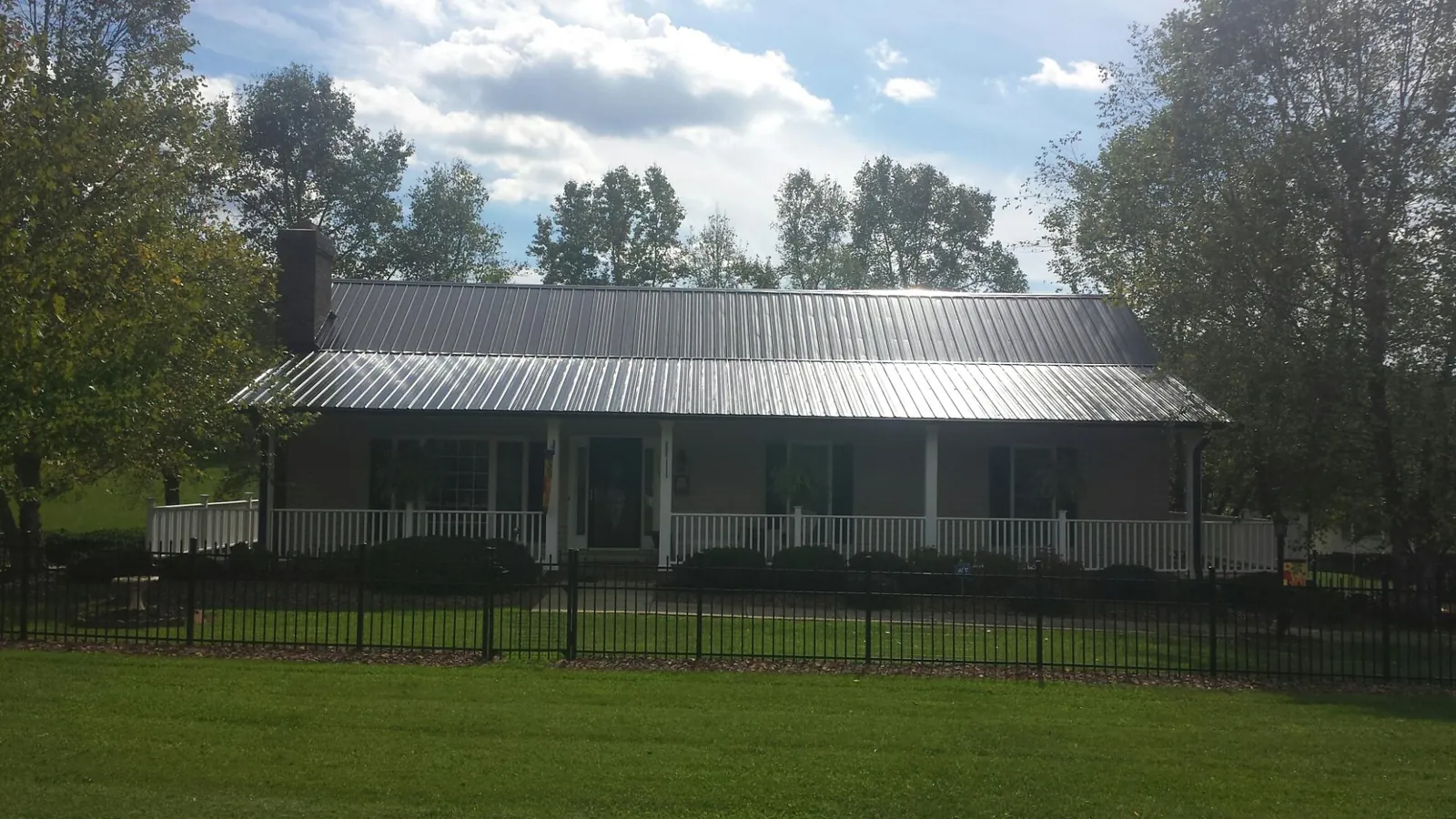 Gray metal roof on a brick ranch with a full width front porch — Gutter Guard Installation work by our crew in Barboursville